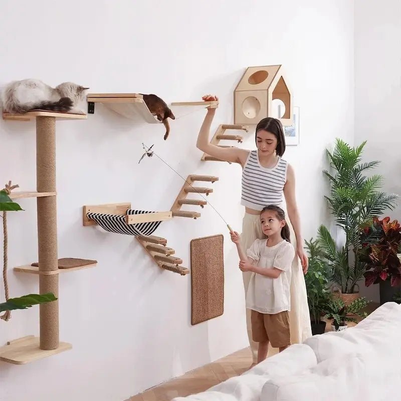 Arbre à chat mural en bois avec plateformes, hamac, maisonnette et chats, mère et fille qui jouent